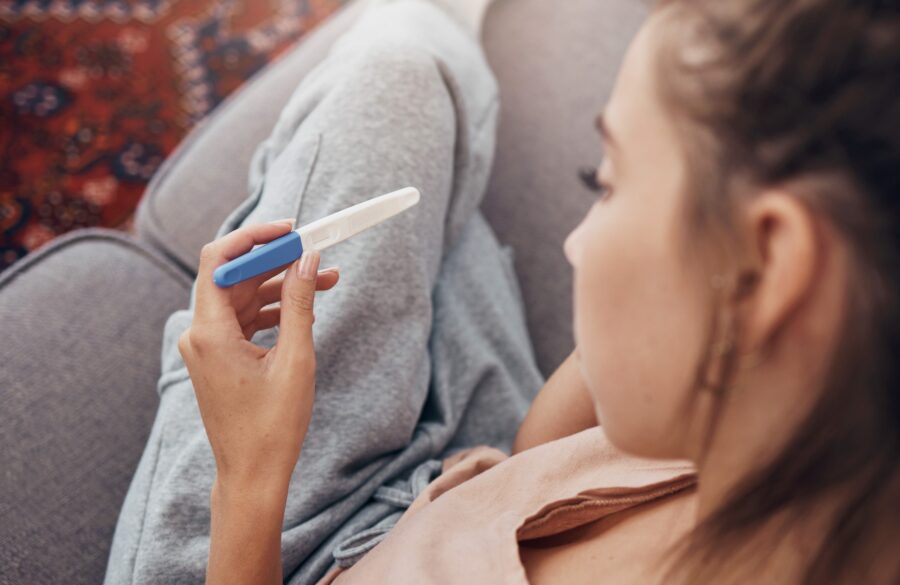 young woman looking at a positive pregnancy test